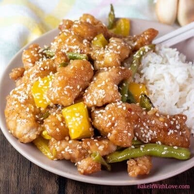 Panda Express honey sesame chicken copycat recipe plated with rice and garnished with more white sesame seeds.